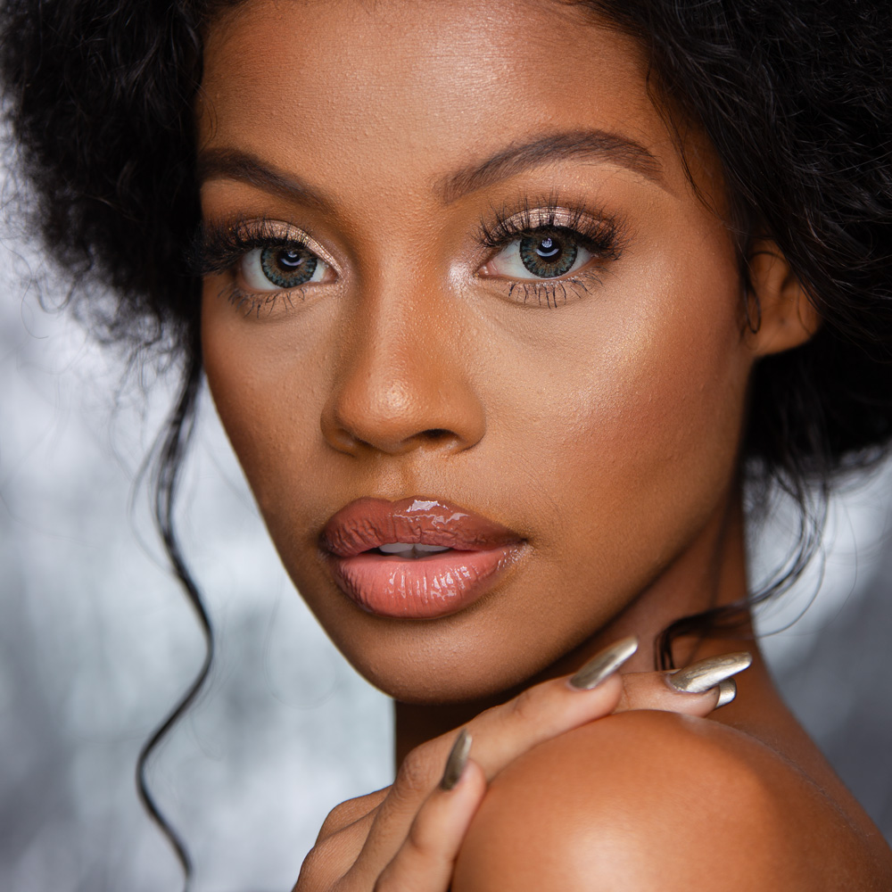 Fashion model image with glamour retouching applied to skin, makeup, and lighting.
