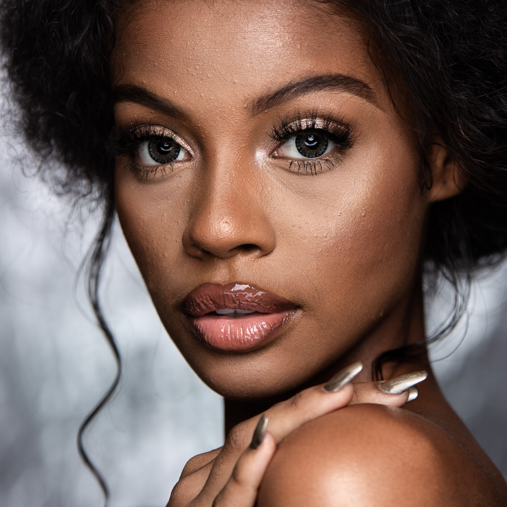 Fashion model image with glamour retouching applied to skin, makeup, and lighting.